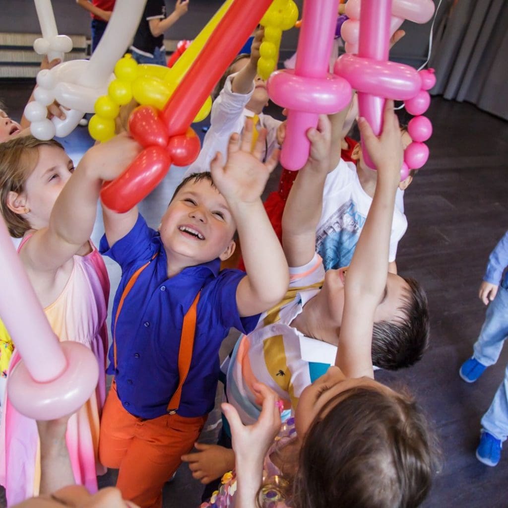Laughing children chasing and tossing balloons Merry kids playing with balloons
