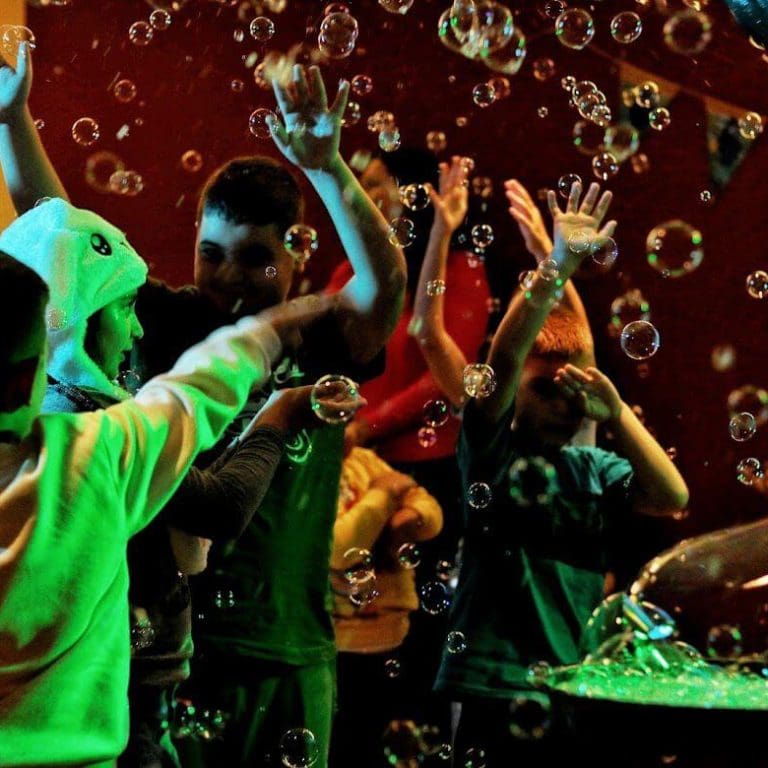 Kinder spielen begeistert im Seifenblasenregen während der Bubble Show