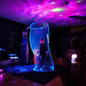 Kind in einer leuchtenden Riesenseifenblase bei einer UV Show in Wien